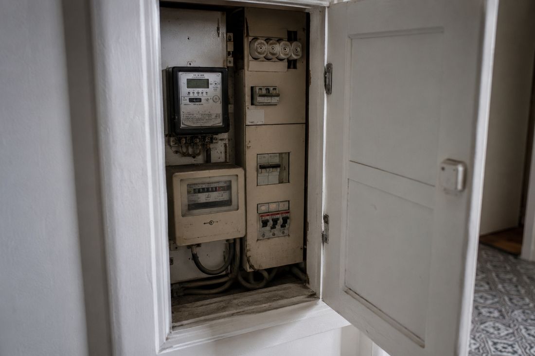 An open domestic electricity meter cupboard in an apartment hallway