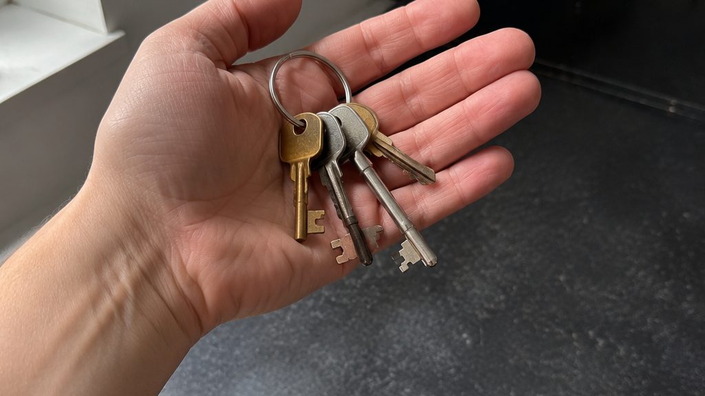 A hand holding a bunch of house keys in a flat